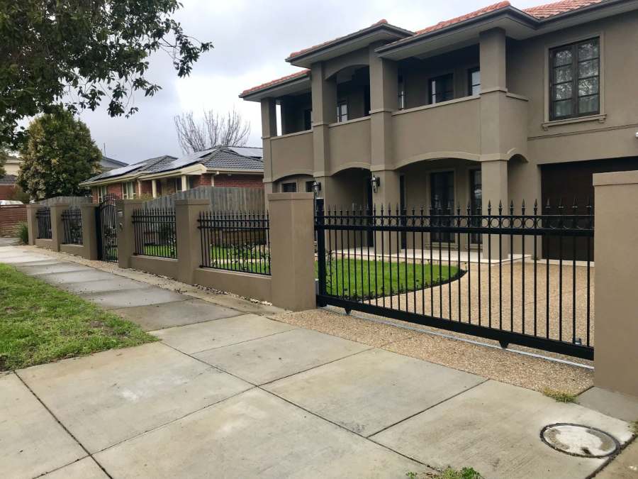 Rendered piers with wrought iron panels and a matching gate in front of a two-storey home